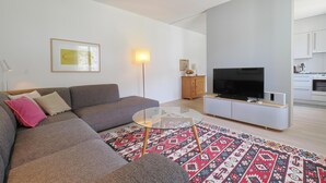 Un salon moderne avec un canapé, une table basse en verre et un téléviseur à écran plat.