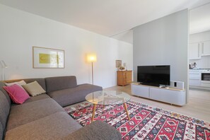 Ein modernes Wohnzimmer mit einer Couch, einem Glastisch und einem Flachbildfernseher.