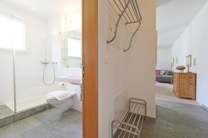 Ein modernes Badezimmer mit einer Duschkabine aus Glas, einer weißen Toilette und einem Handtuchhalter aus Metall.