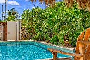 A swimming pool surrounded by lush tropical plants and a stone wall. - Picaron 19G - B (Santa Cruz)