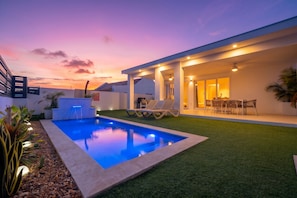 Ein modernes Haus mit Swimmingpool, Außenbereich mit Sitzgelegenheiten und einer gut beleuchteten Terrasse.