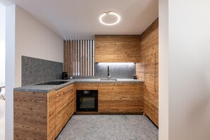 Eine kompakte Küche mit Holdekor-Schränken, einer Granitarbeitsplatte, einem eingebauten Backofen und einer modernen Leuchte.