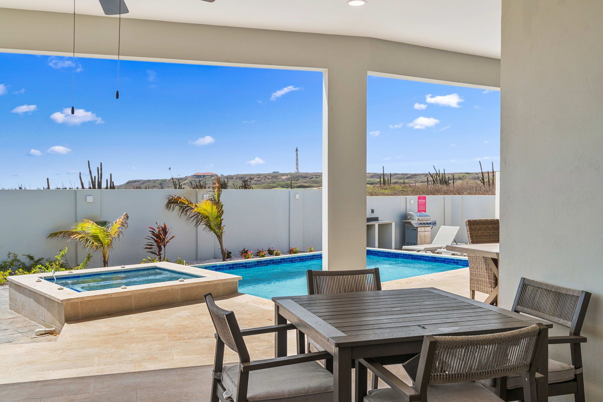 Un área de piscina con jacuzzi, mobiliario exterior y vistas al paisaje.