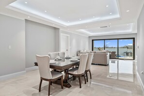 Un comedor con mesa lista para cuatro personas, un sofá y vista a una piscina.