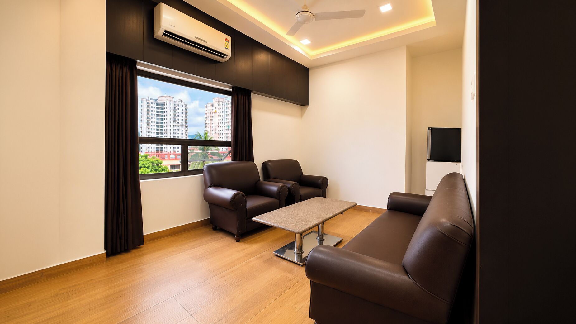 A modern living room with a sofa, two armchairs, a coffee table, and a TV.