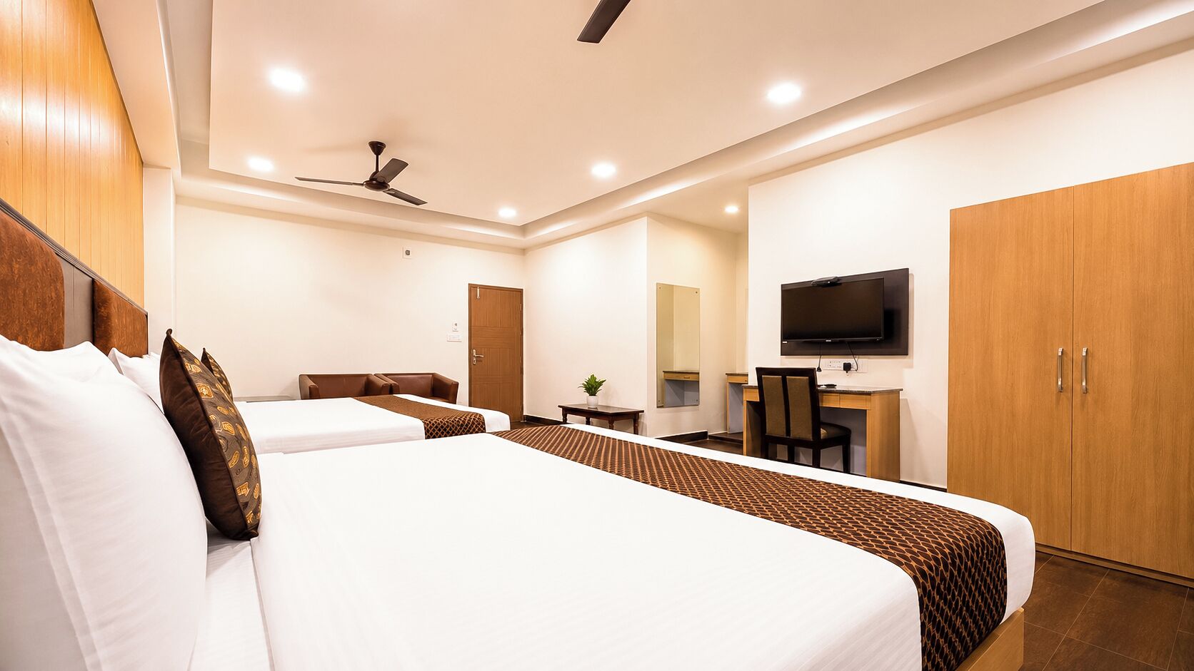 A hotel room with a large bed, a desk, a television, and a wardrobe.