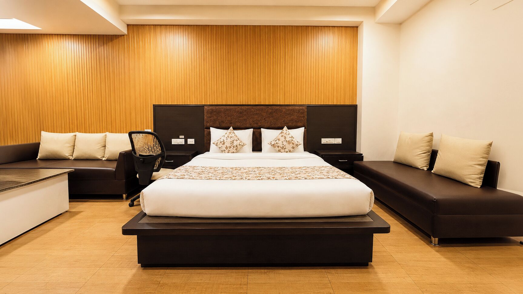 A modern bedroom with a large bed, a sofa, a desk, and a chair.