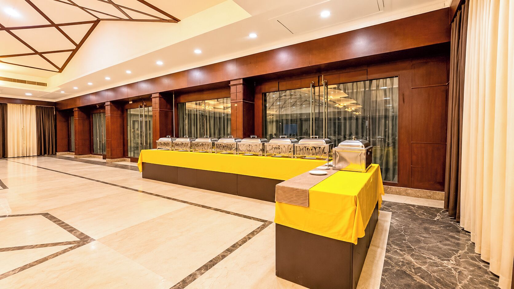 Ein Hotelkonferenzraum mit einem langen Tisch, der mit Gelb bedeckt ist, ausgestattet mit mehreren Speiseausgabestationen.