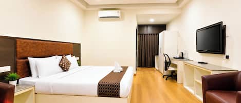 Una habitación de hotel con una cama, un escritorio, una silla, un televisor y un equipo de aire acondicionado.