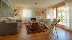 Ein Wohnzimmer mit einer Couch, einem Sessel, einem Couchtisch und einem Fernseher.