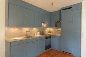 Eine moderne Küche mit blauen Schränken, einer Edelstahl-Dunstabzugshaube und einem eingebauten Backofen.