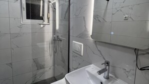A bathroom with a toilet, a sink, a shower, and a mirror. - Apartment Lavaran 2 (Vir)
