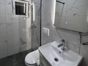 A bathroom with a toilet, a sink, a shower, and a mirror. - Apartment Lavaran 2 (Vir)