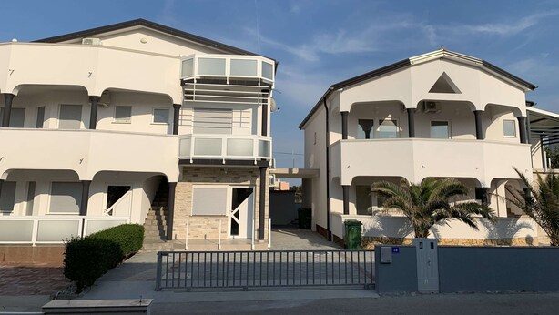 A two-story residential building with a balcony, a gated entrance, and a small garden area. - Apartment Lavaran 2 (Vir)