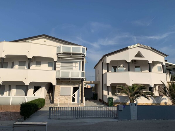 A two-story residential building with a balcony, a gated entrance, and a small garden area. - Apartment Lavaran 2 (Vir)