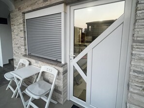 A room with a stone wall, a closed window with blinds, a white door, and a small table with two chairs. - Apartment Lavaran 2 (Vir)