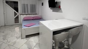 A bedroom with a bed, a desk, a chair, a TV on the wall, and a door leading to a balcony. - Apartment Lavaran 2 (Vir)