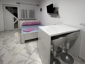 A bedroom with a bed, a desk, a chair, a TV on the wall, and a door leading to a balcony. - Apartment Lavaran 2 (Vir)