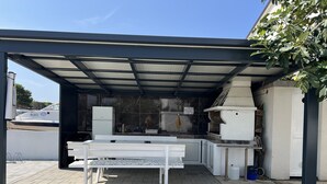 An outdoor kitchen area with a grill, a refrigerator, and a table. - Apartment Lavaran 2 (Vir)
