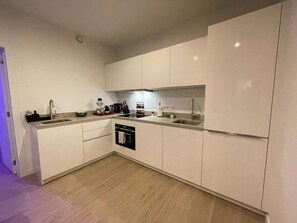 Eine moderne Küche mit weißen Schränken, einem Einbauofen und einer Spüle aus Edelstahl.