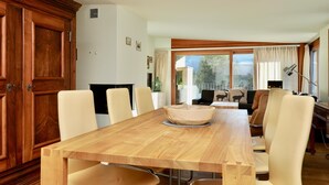 Un comedor con una mesa y sillas de madera, un tazón grande en el centro, y vistas al exterior a través de una ventana.