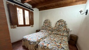Een slaapkamer met een bed, een raam, een wandlamp en een betegelde vloer.