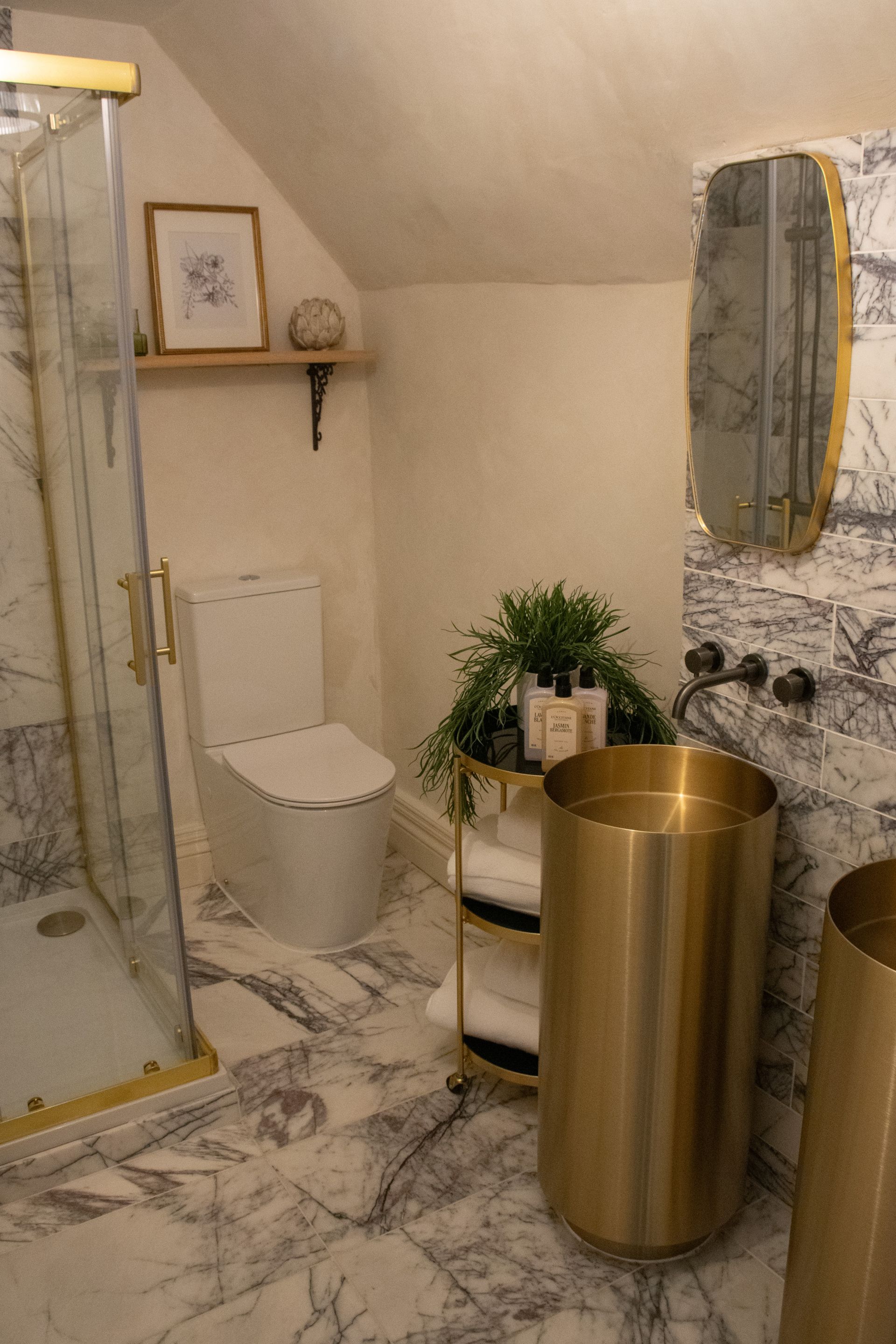Un baño con cabina de ducha de vidrio, inodoro, lavamanos con resalte de mármol y un espejo grande.
