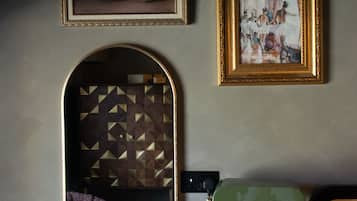 A room with a desk, a lamp, a mirror, and two framed artworks on the wall.