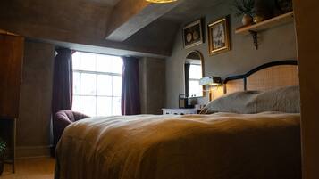 A bedroom with a large bed, a dresser, a mirror, and a window with curtains.