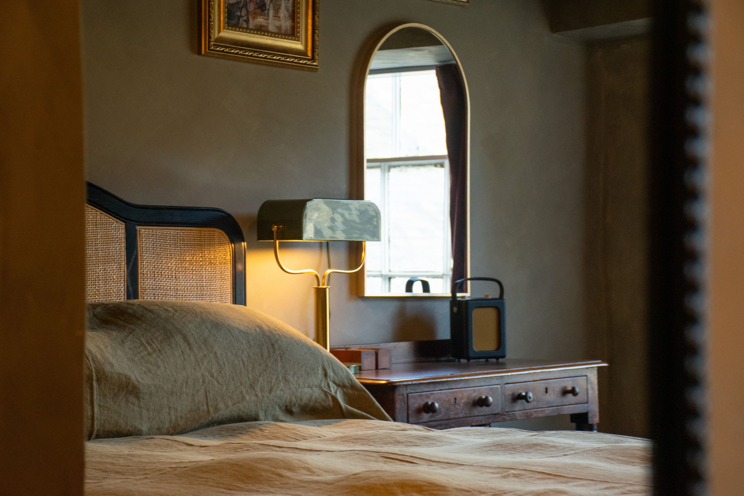 Un dormitorio con cama, cómoda, espejo y lámpara.