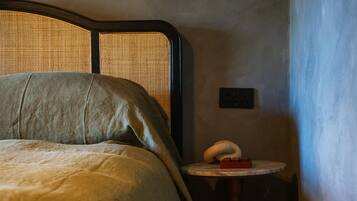 A bed with a headboard, a bedside table with a lamp, and a wall socket.