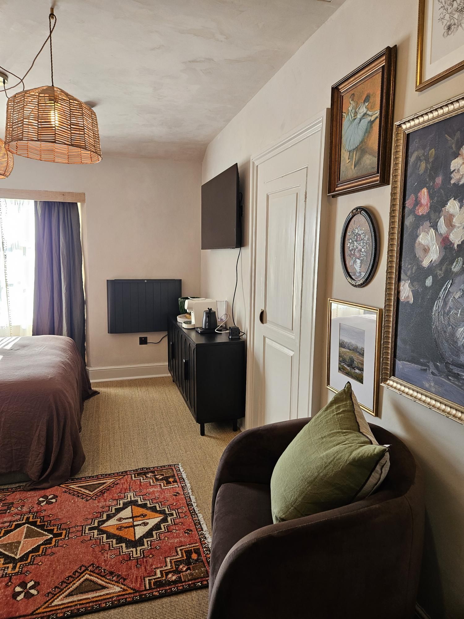 A bedroom with a bed, a TV, a dresser, and a sofa.