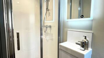 A modern bathroom with a glass-enclosed shower, a white sink, and a mirror above the sink.
