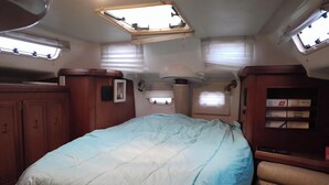 Interior compacto de uma RV, com uma cama, uma pequena janela e um armário.