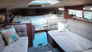 Um espaço interno compacto com cama, sofá e um banco.