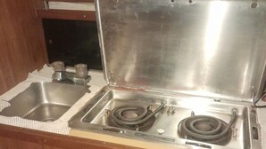 Uma cozinha compacta com uma pia de aço inoxidável, dois fogões e um pequeno balcão.