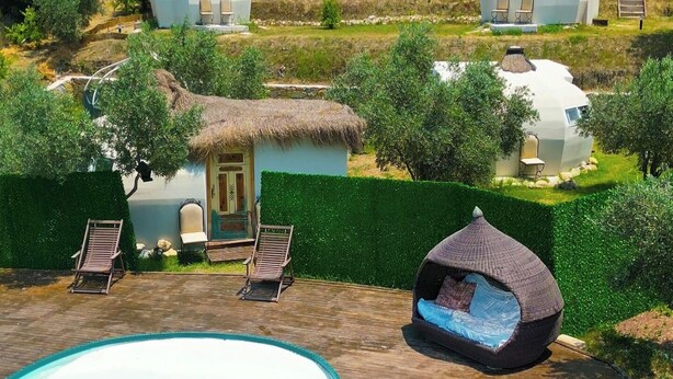 A pool area with a thatched-roof structure and lounge chairs. - Vita Nova Hotel (Kumluca)
