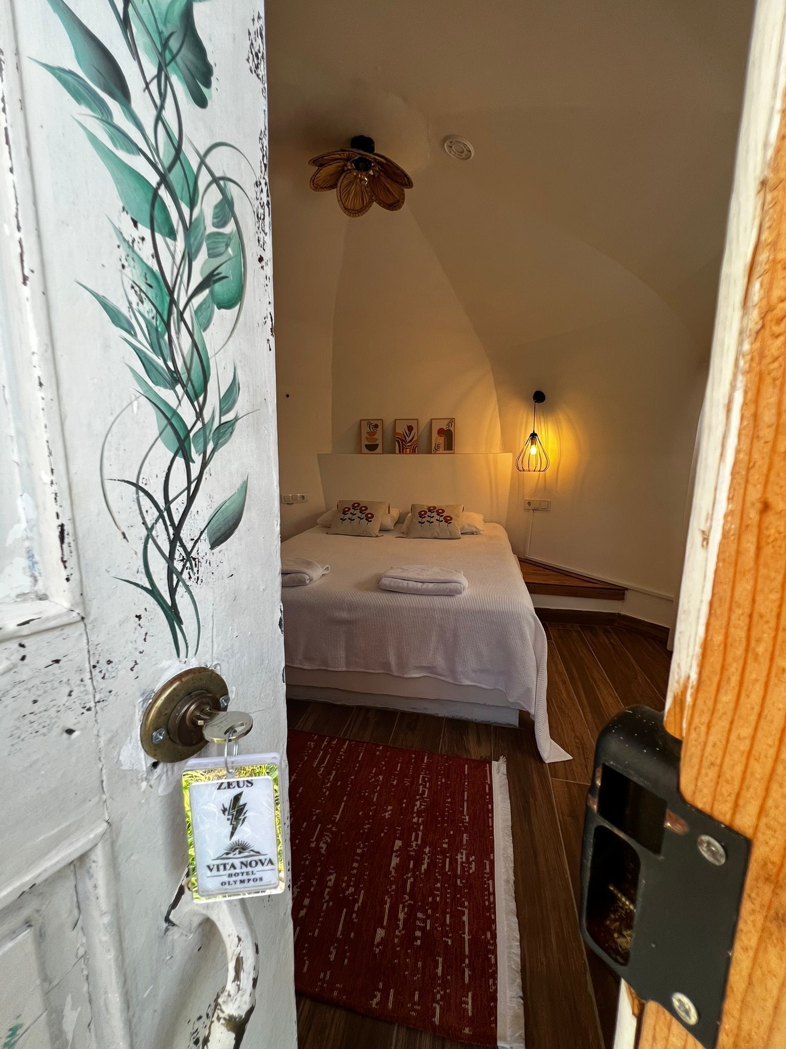 Quarto com cama, tapete vermelho, ventoinha no teto e obras de arte nas paredes.
