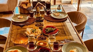 A dining table set with various dishes, glasses, and cutlery in a well-lit room with a view of the outdoors. - Vita Nova Hotel (Kumluca)