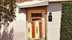 A rustic wooden door with decorative carvings, a small wooden bench, and a wall-mounted mailbox. - Vita Nova Hotel (Kumluca)