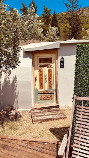A rustic wooden door with decorative carvings, a small wooden bench, and a wall-mounted mailbox. - Vita Nova Hotel (Kumluca)