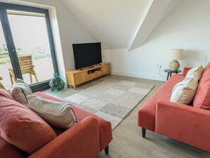 Ein modernes Wohnzimmer mit Fernseher, zwei Sofas, einem Teppich und einem Holzschrank.