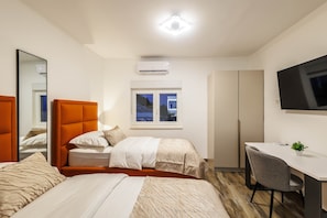 Ein Hotelzimmer mit zwei Betten, einem Schreibtisch, einem Fernseher und einem Fenster.