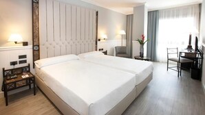 A hotel room with a large bed, two bedside tables, a desk, and a chair. - Hotel Ini (Madrid)