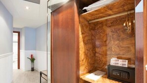 A room with a wooden wardrobe, a small desk with a telephone, and a plant. - Hotel Ini (Madrid)