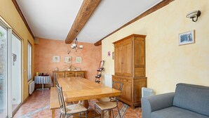 A dining area with a wooden table and chairs, a sofa, and a cabinet. - Bed and Breakfast 'Le Clos Mazerolles - Chambre Bleue' with Shared Pool, Wi-Fi and Air Conditioning (Cruzy)