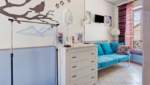 A room with a bed, a dresser, a wall-mounted TV, and a window with curtains. - Bed and Breakfast 'Le Clos Mazerolles - Chambre Bleue' with Shared Pool, Wi-Fi and Air Conditioning (Cruzy)
