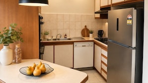 A modern kitchen with a dishwasher, refrigerator, and a wooden cabinet. - Family-Friendly 2BR Villa with Private Courtyard (Malvern East)