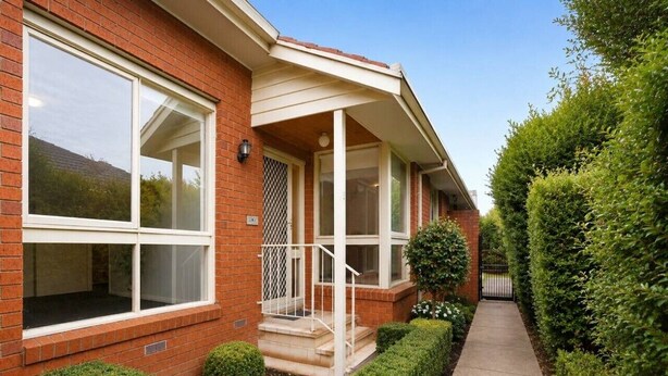 A two-story brick house with a covered porch, a small front yard, and a pathway leading to the front door. - Family-Friendly 2BR Villa with Private Courtyard (Malvern East)