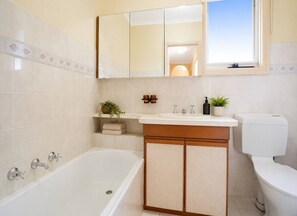 Ein Badezimmer mit Badewanne, Toilette, Waschbecken und Spiegel.